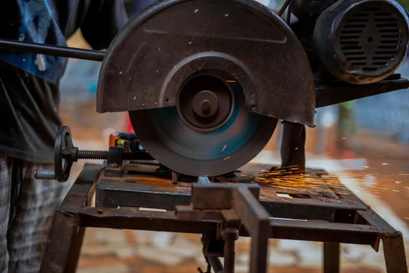 Close-up of a circular saw blade cutting metal, emitting sparks, in an industrial setting