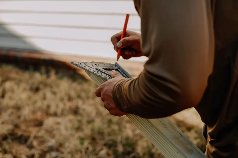 Carpenter measuring wood with a square outdoors, showcasing precise craftsmanship and manual labor
