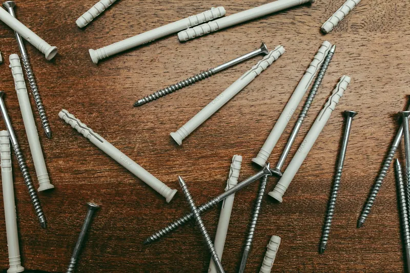 High-angle view of metal screws and plastic wall plugs on a wooden surface