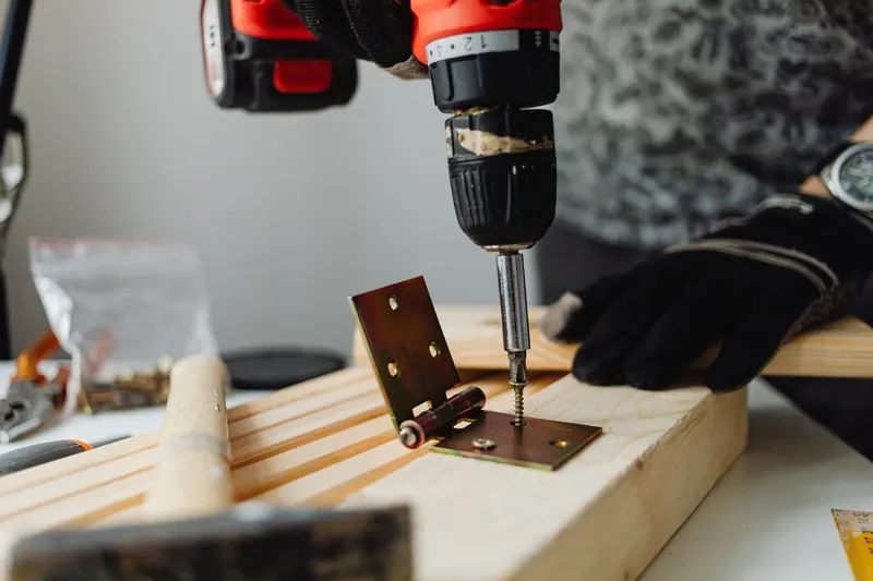 Close-up of a skilled carpenter using a power drill on wood in a workshop